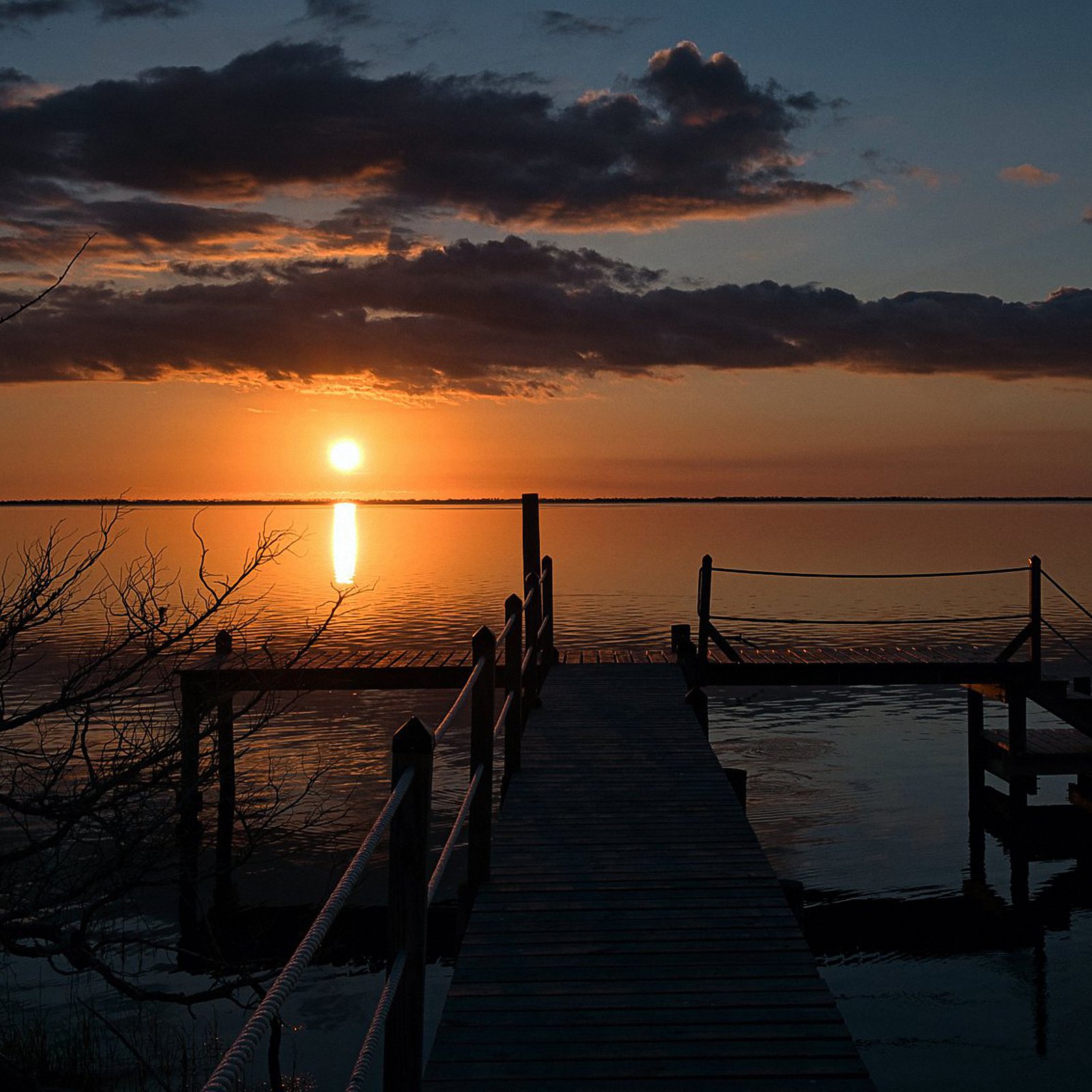 A sunset with a dock in the foreground, looking toward Cape San Blas